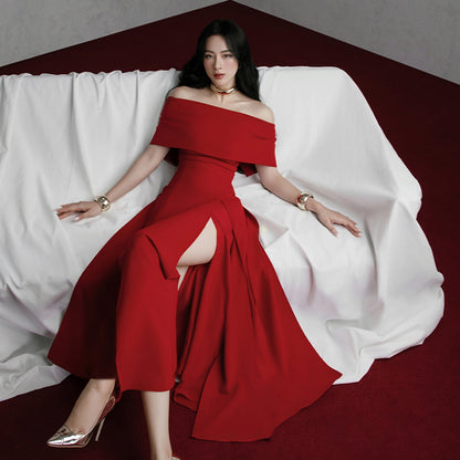 Woman in a red off-shoulder dress sitting on a white draped fabric.