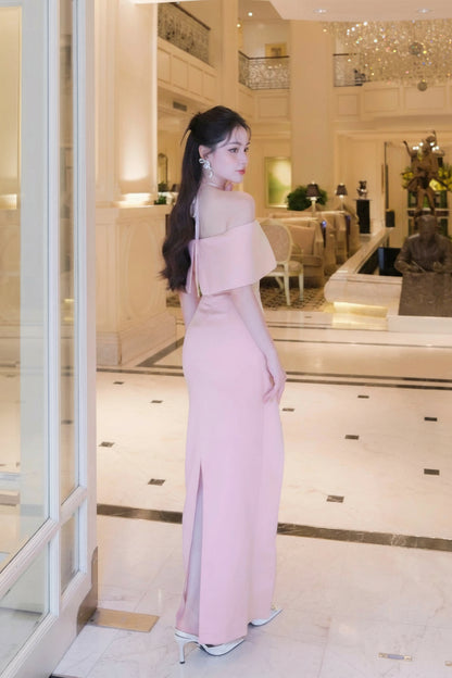 Woman in a pink evening gown standing in a stylish interior setting.