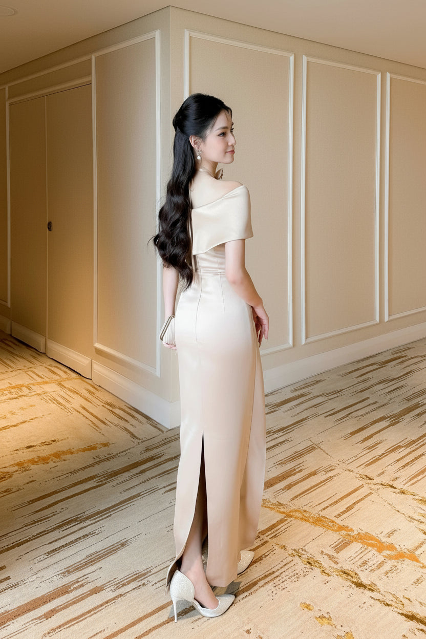 Woman in a beige evening gown standing in an elegant room with wooden flooring.