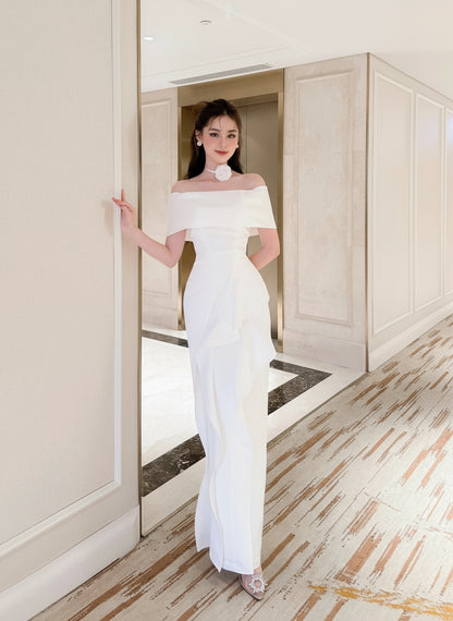 Woman in a white off-shoulder gown standing in a hallway.