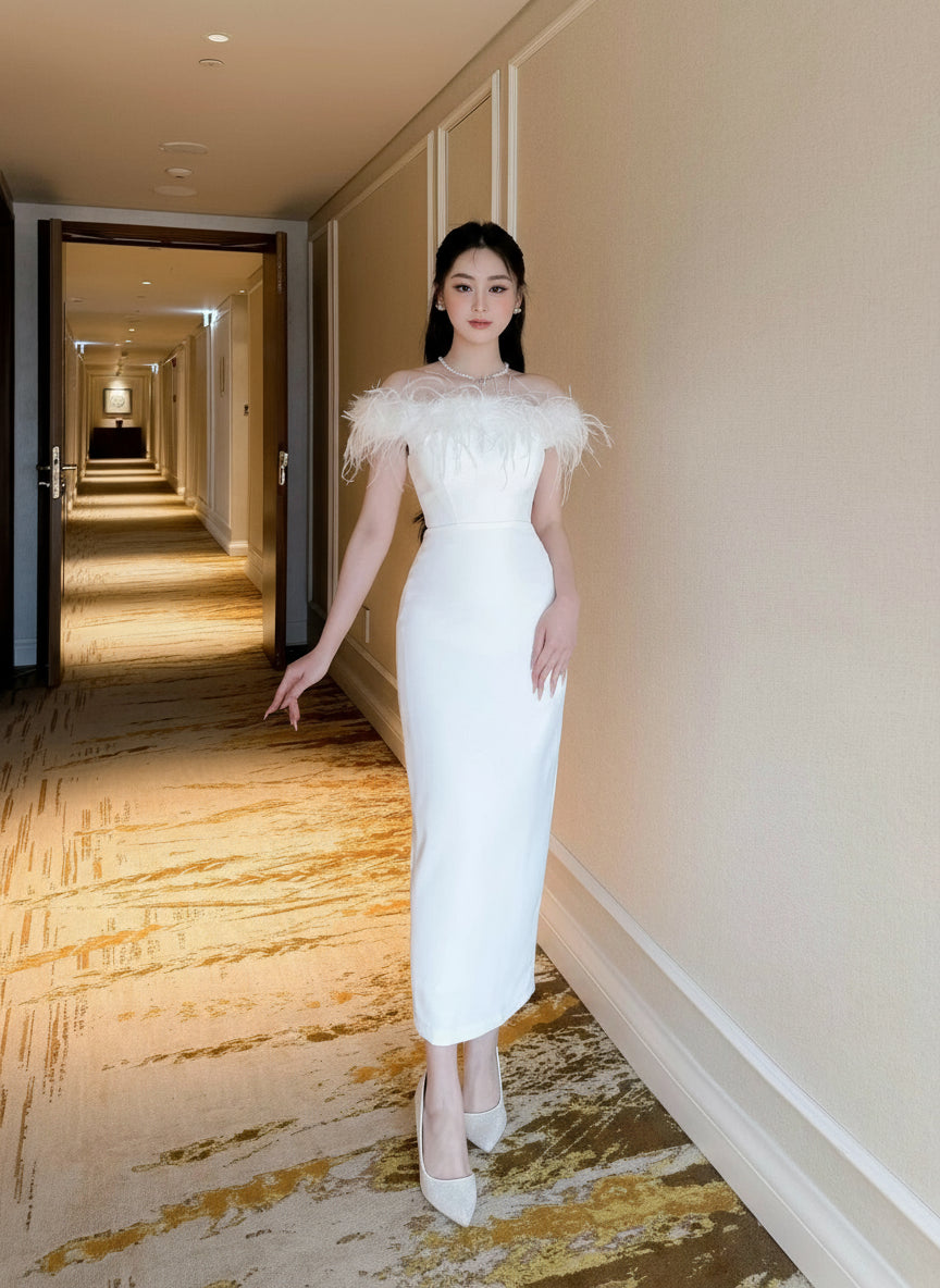 Woman in a white dress with feathered shoulders standing in a hotel hallway.