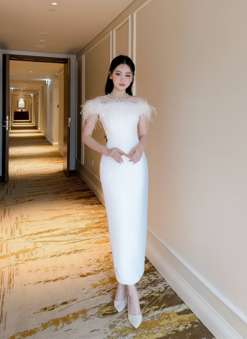 Woman in a white dress with feathered shoulders standing in a hallway.