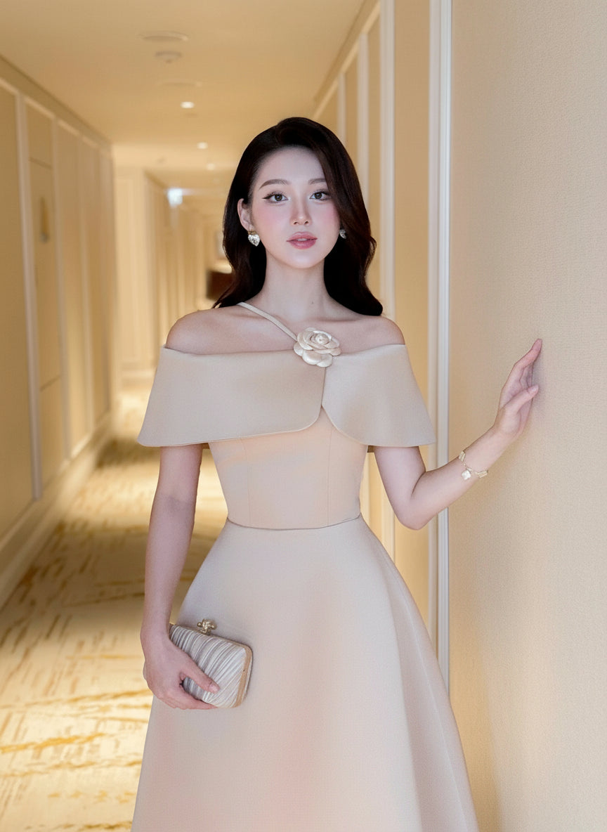 Woman in a beige off-shoulder dress standing in a hallway.