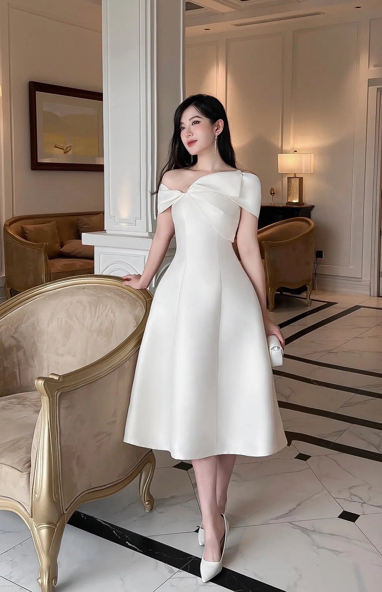 Woman in a white dress standing in an elegant interior setting