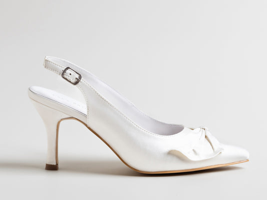 White high-heeled shoe with a bow on a light gray background
