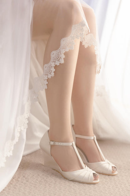 White lace-trimmed stockings and white shoes on a neutral background