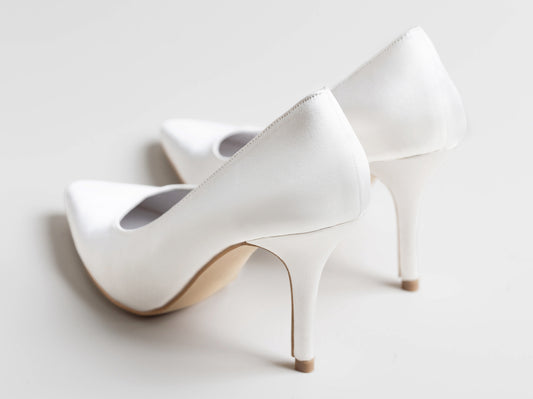 White high-heeled shoes on a light gray background