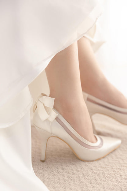 White high-heeled shoes with a bow on a light background
