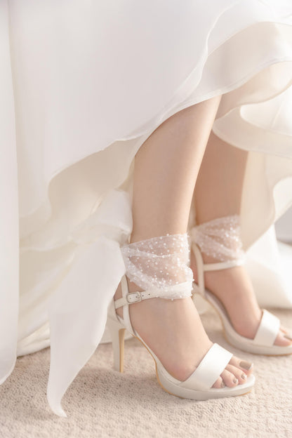 White wedding dress with lace-trimmed high-heeled shoes on a light background