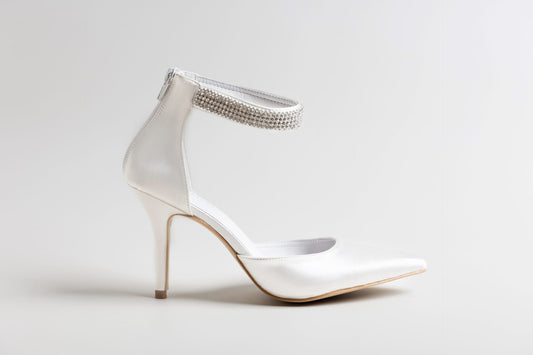 White high-heeled shoe with embellished ankle strap on a light gray background