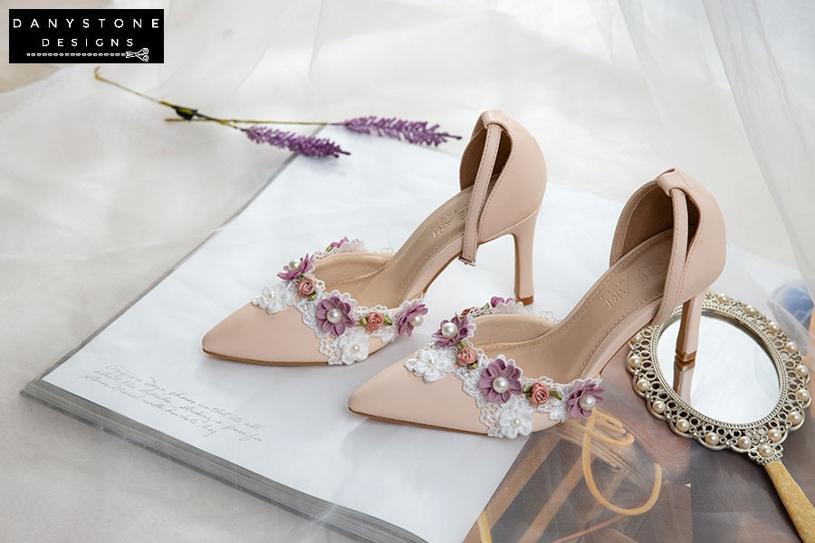 Stylish nude bridal heels with floral lace trim, 9cm heel, made from matte pink cream leather, arranged on a book.