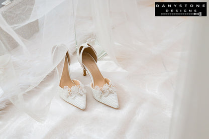 Pair of white bridal shoes with chiffon butterfly wings and 9cm heels, showcased on a white fabric surface with a glittery box.