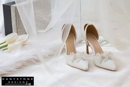 Pair of white bridal shoes with chiffon butterfly wings and 9cm heels, showcased on a white fabric surface with a glittery box.