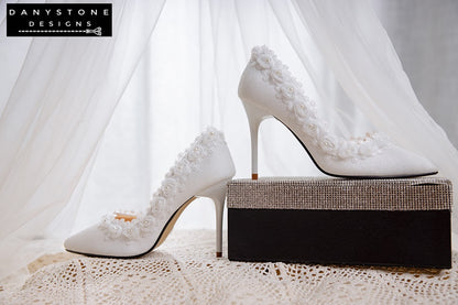 Close-up of the back and side of white wedding shoes with rose lace trim, showing the intricate details of the design.