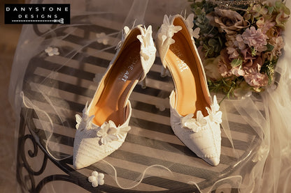 Side view of white lace wedding shoes with butterfly decor and 9cm heels, displayed with a glittery box and a sheer fabric backdrop.