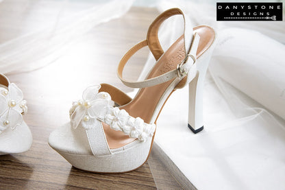 Close-up of Elegant White Floral Wedding High Heels with a double floral toe strap, lightly shimmering metallic leather.