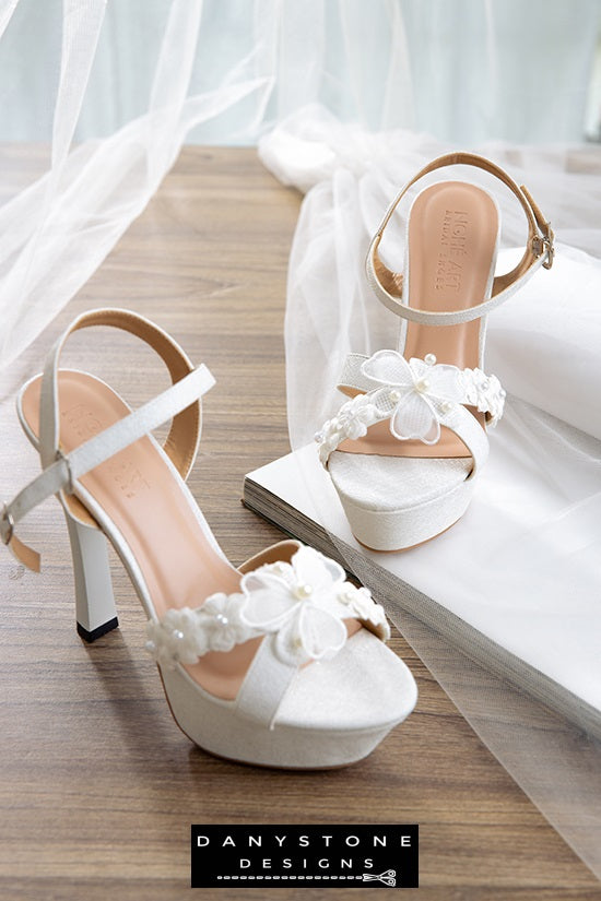 Close-up of Elegant White Floral Wedding High Heels with a double floral toe strap, lightly shimmering metallic leather.