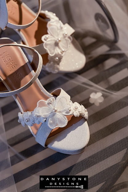 Elegant White Floral Wedding High Heels showcasing the double floral toe strap and lightly shimmering metallic leather.