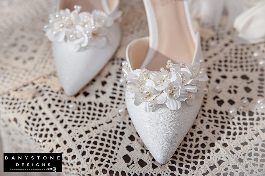 Top view of Elegant White Floral Wedding Shoes with floral decorations and ankle straps, displayed on a lace tablecloth.