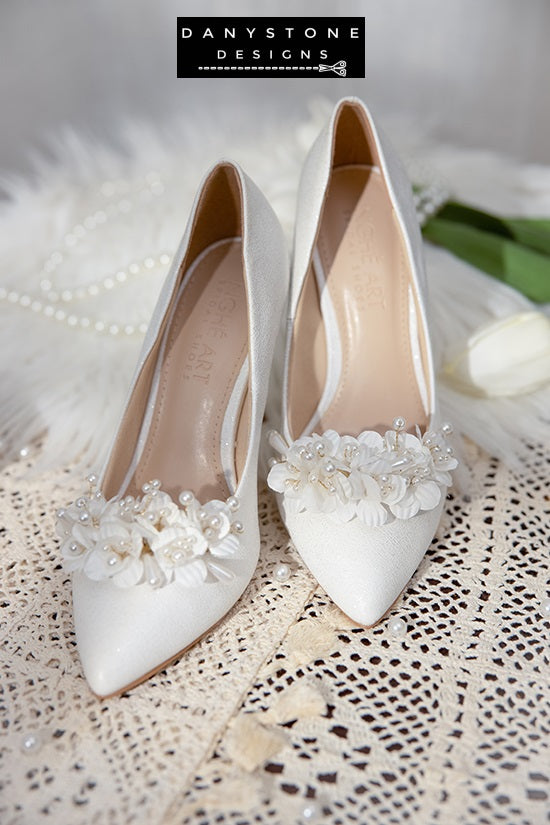 Elegant White Metallic Leather Wedding Heels with floral embellishments, displayed with a candle and white tulip.