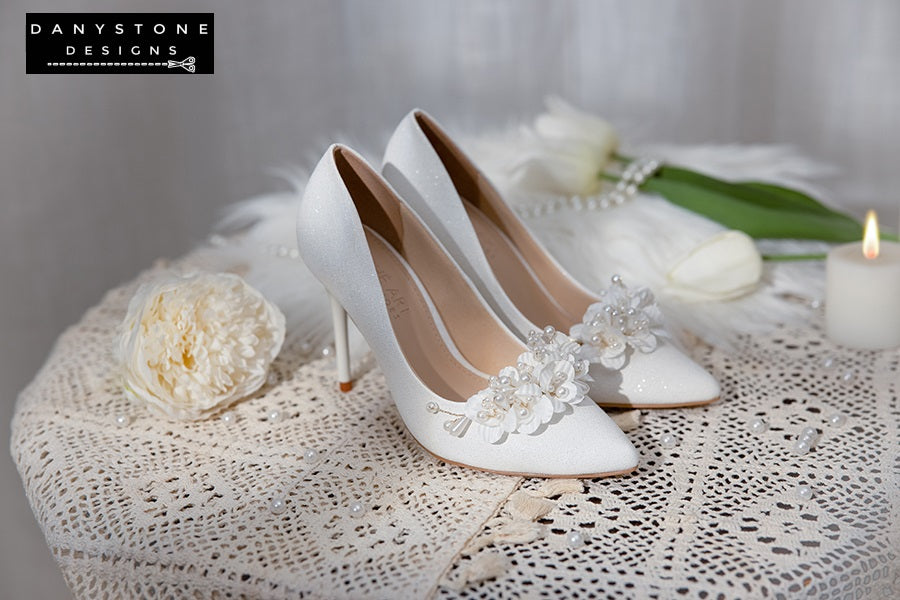 Pair of Elegant White Metallic Leather Wedding Heels with floral embellishments, displayed with a white teacup and tulip.