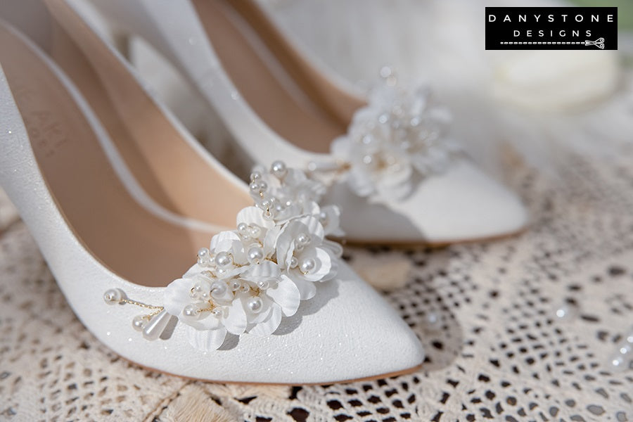 Elegant White Metallic Leather Wedding Heels with floral embellishments on a lace tablecloth.