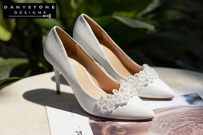 "Detailed shot of 10cm wedding shoes with white crystal bead flowers on scratched leather"