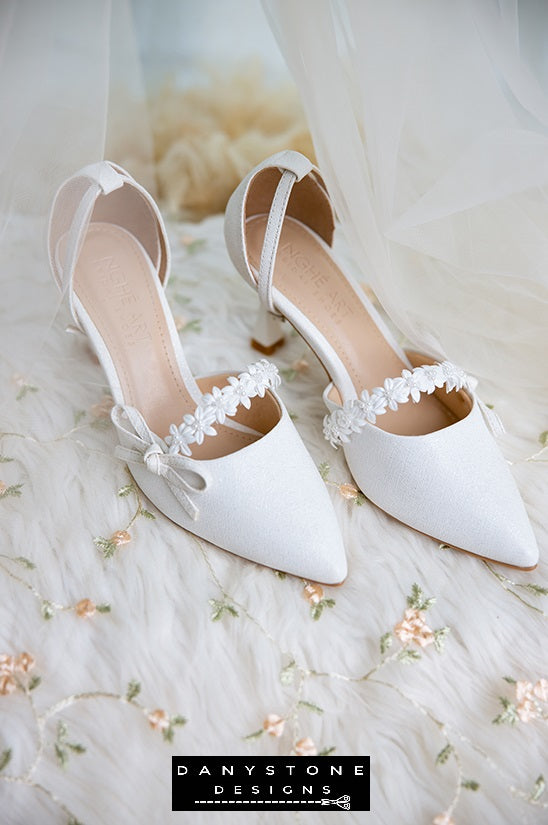 Stylish white bridal shoes with floral straps and bows, 7cm heels, perfect for a modern bride.