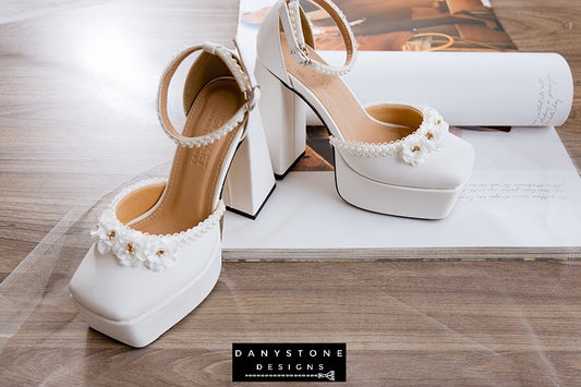 Elegant white bridal high heels with double square toe, floral trim, and 13cm heel, crafted from matte white leather.