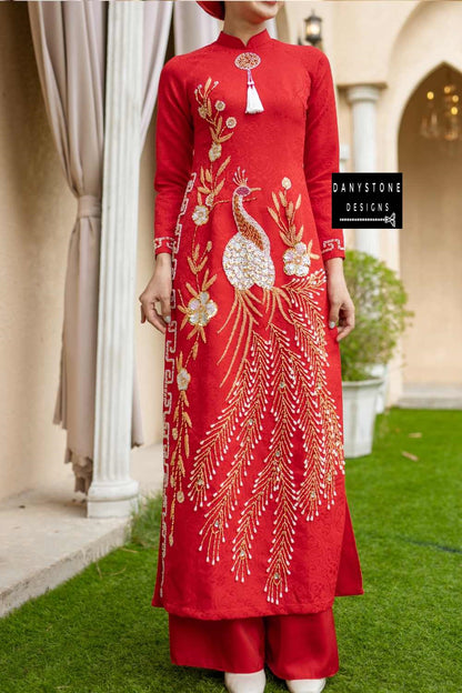 Red brocade Áo Dài with elegant phoenix embroidery and luxurious design, worn by a smiling bride.