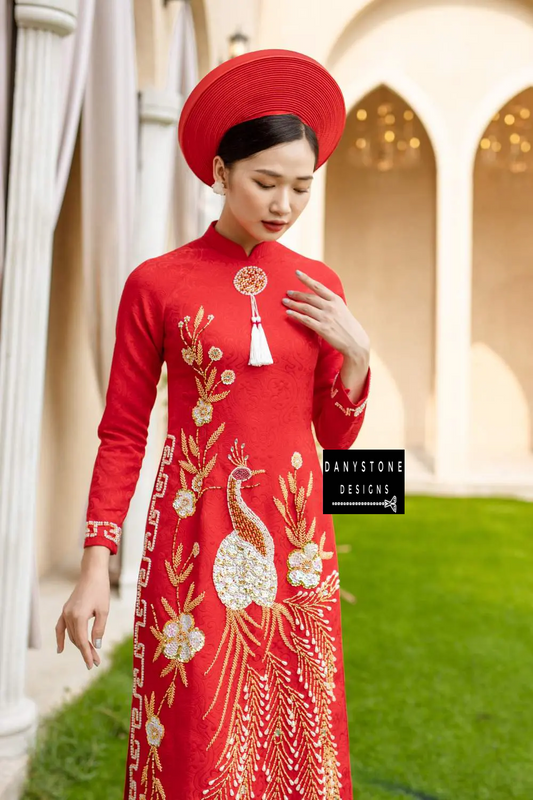 Elegant woman wearing a royal red brocade Áo Dài with phoenix embroidery, standing and smiling.