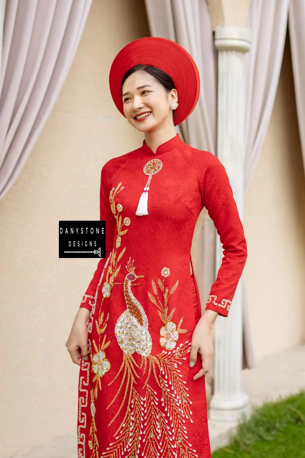 Full-length view of a bride in a red brocade Áo Dài with detailed phoenix embroidery and beading