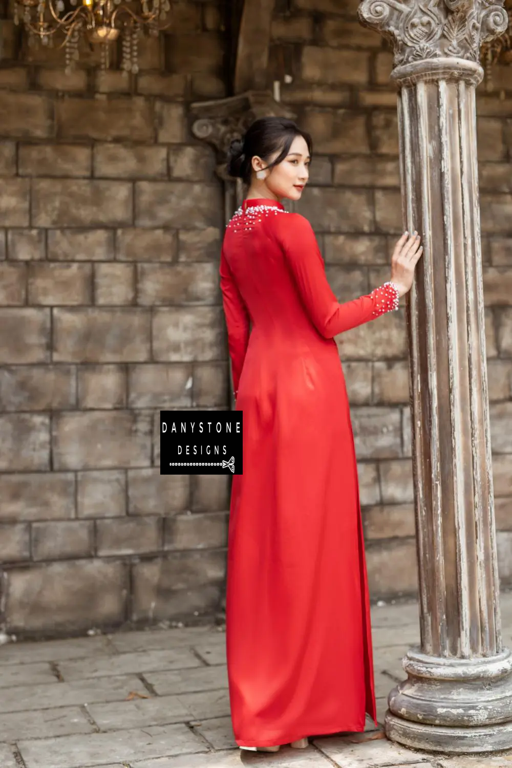 Close-up of a red silk bridal Áo Dài with pearl-embellished neckline and cuffs.