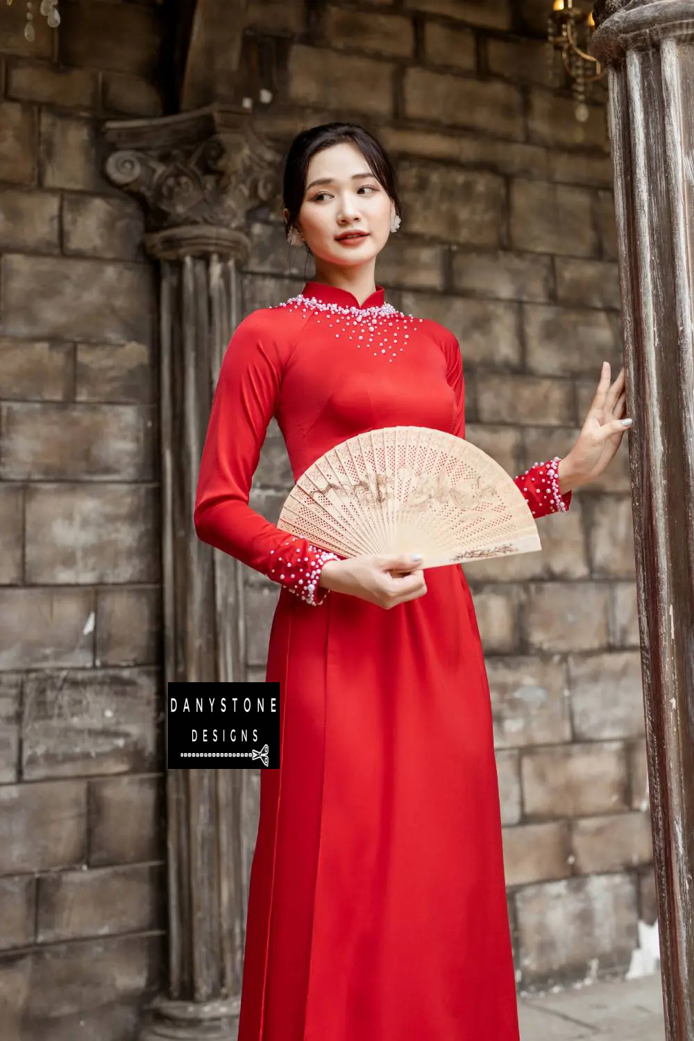 Full-length view of a bride in a red silk Áo Dài with intricately studded pearl neckline and cuffs.