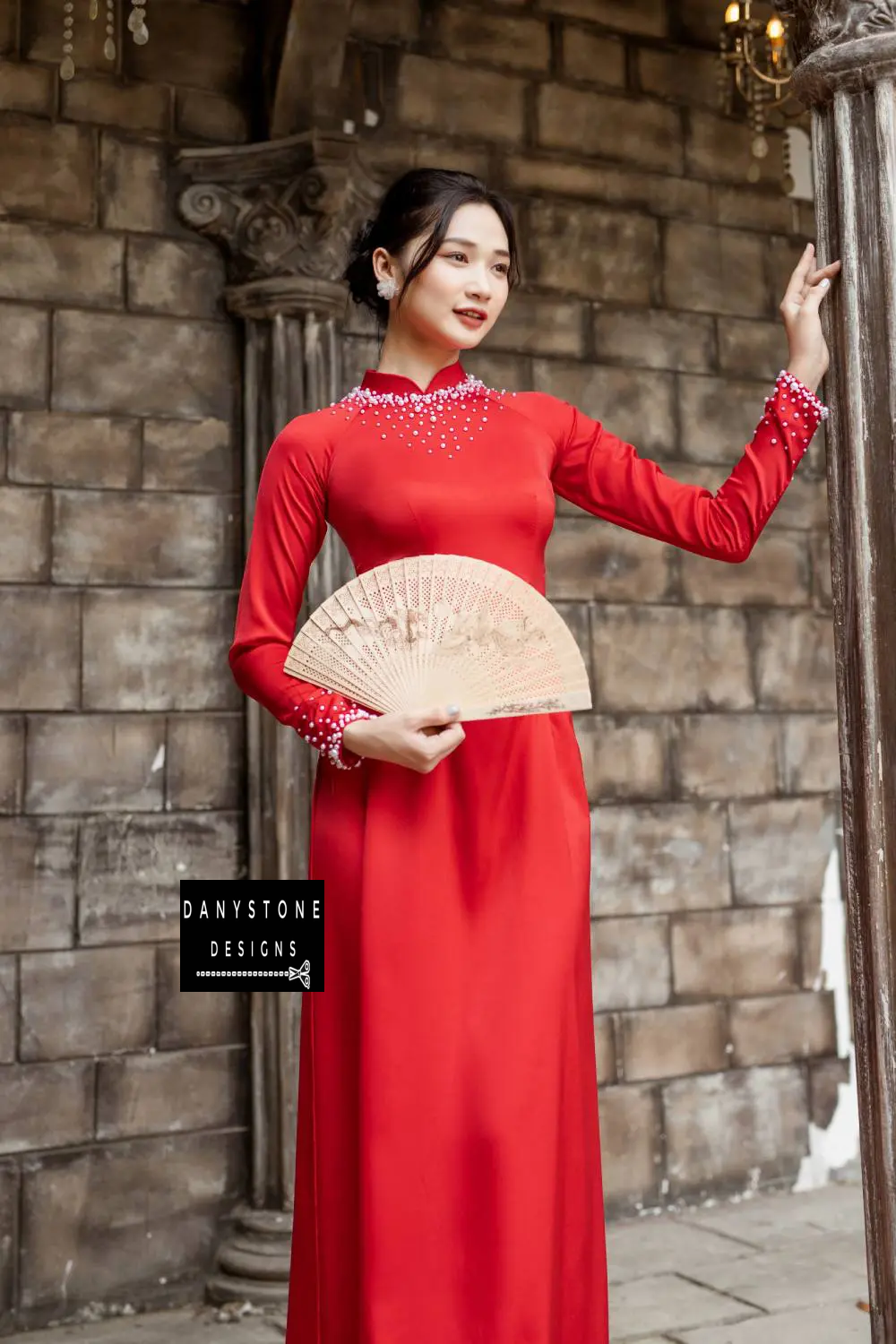  Woman in a red silk Áo Dài, showcasing the pearl-embellished neckline and cuffs.