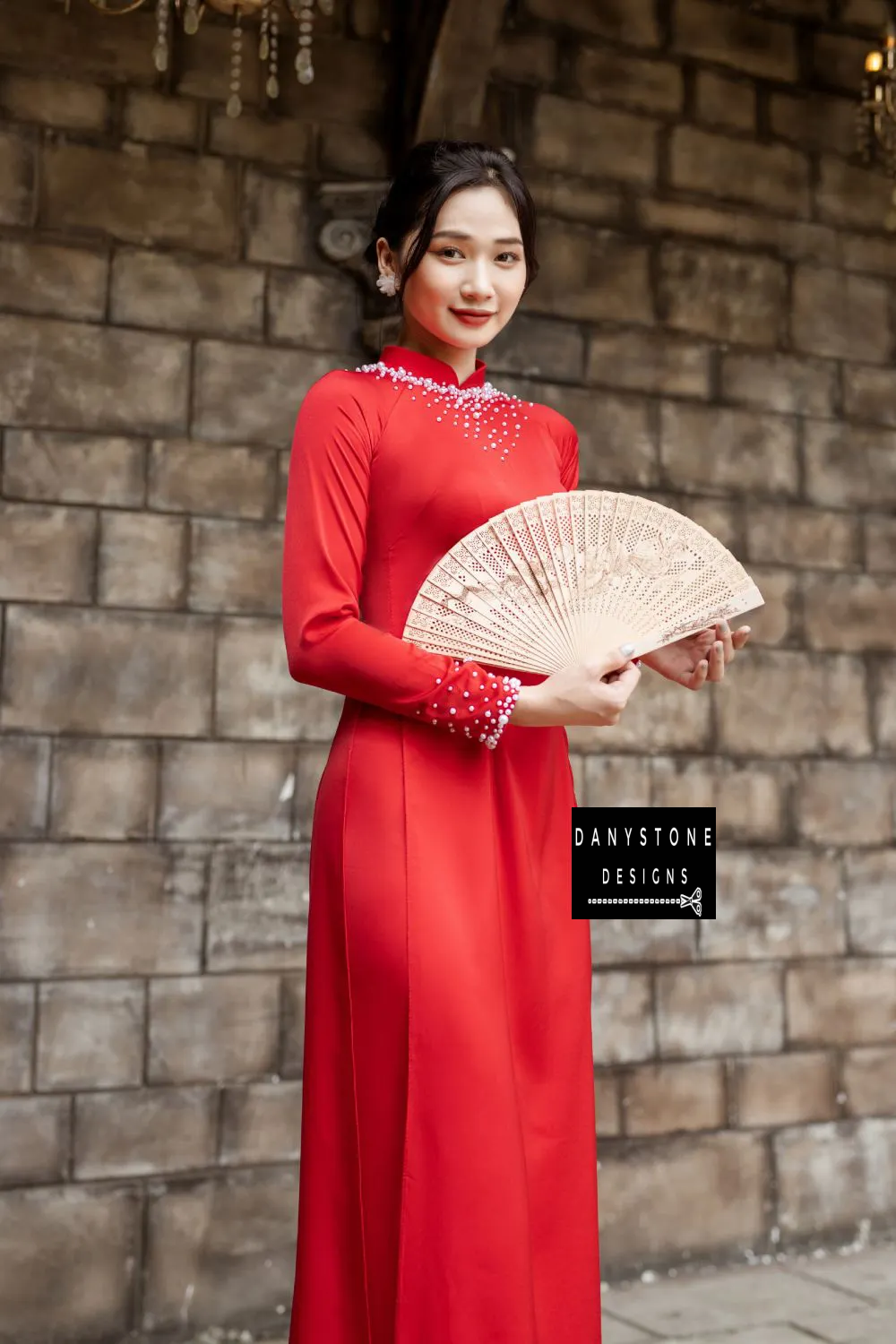 Red silk Áo Dài with luxurious pearl details on the neckline and cuffs, worn by a bride.