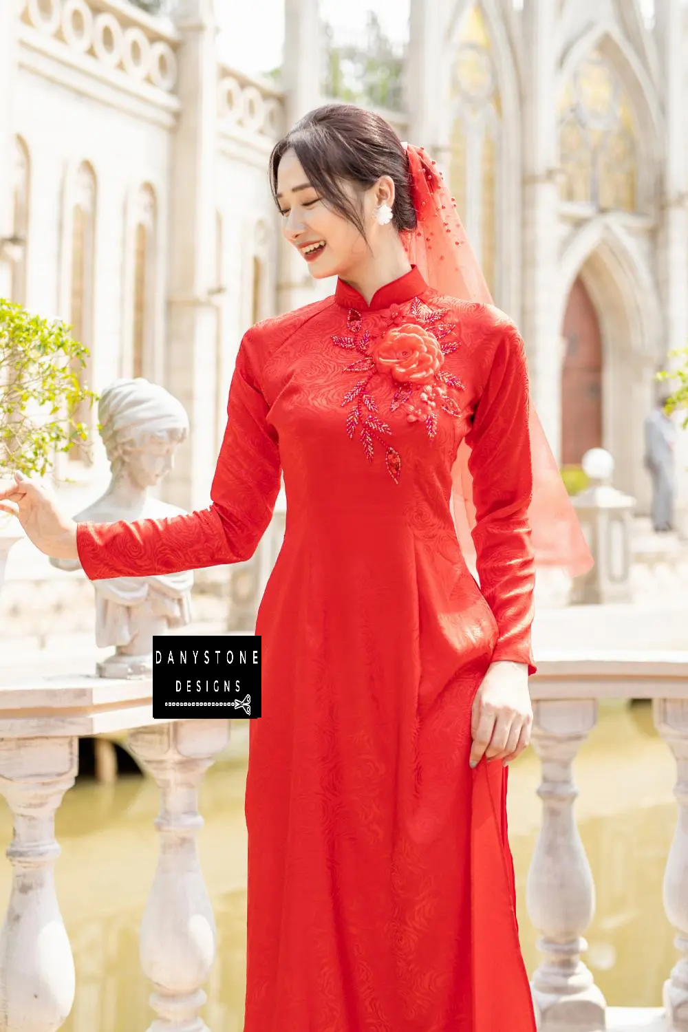  Close-up of a red brocade Áo Dài with a large crimson flower and beaded leaves on the chest.