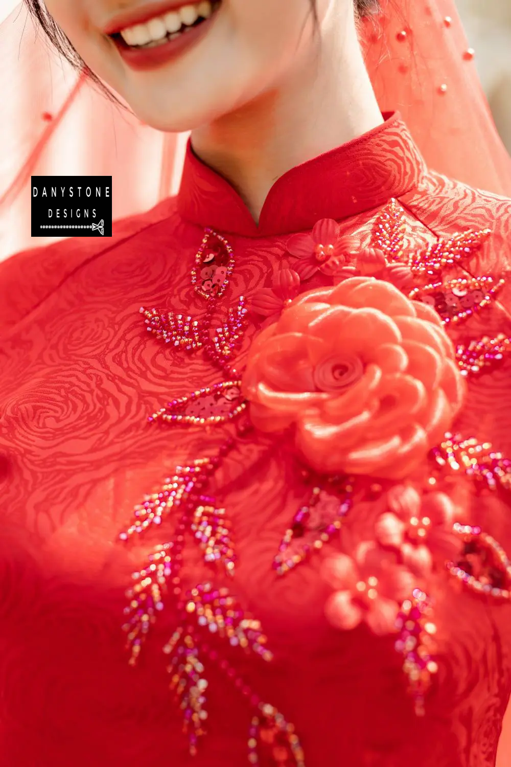 Detailed view of the floral embellishments on a red brocade Áo Dài, highlighting the intricate beading.