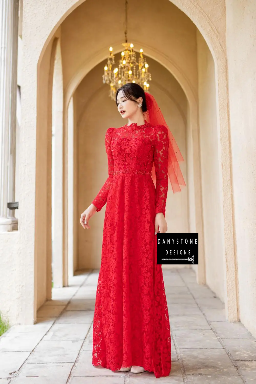 A smiling bride in a Red Lace Bridal Ao Dai with pearls, capturing the vibrant crimson hue and the dress's elegant appeal.