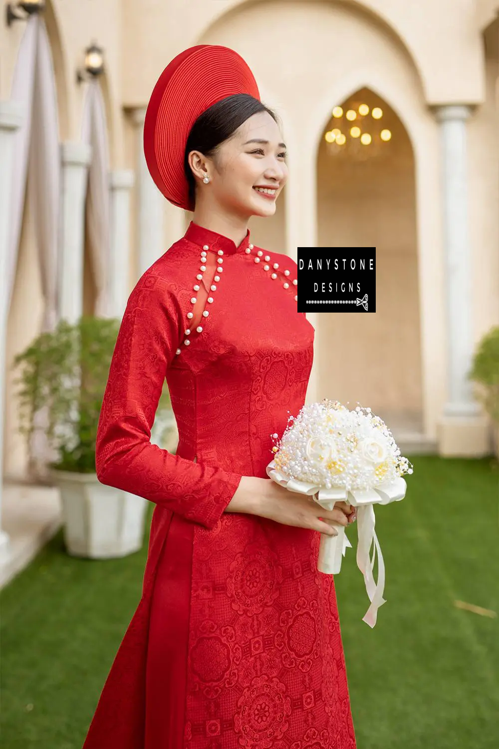 Full-length view of a smiling bride in the Pearl-Trimmed Brocade Bridal Ao Dai, highlighting the vibrant crimson color and elegant design.