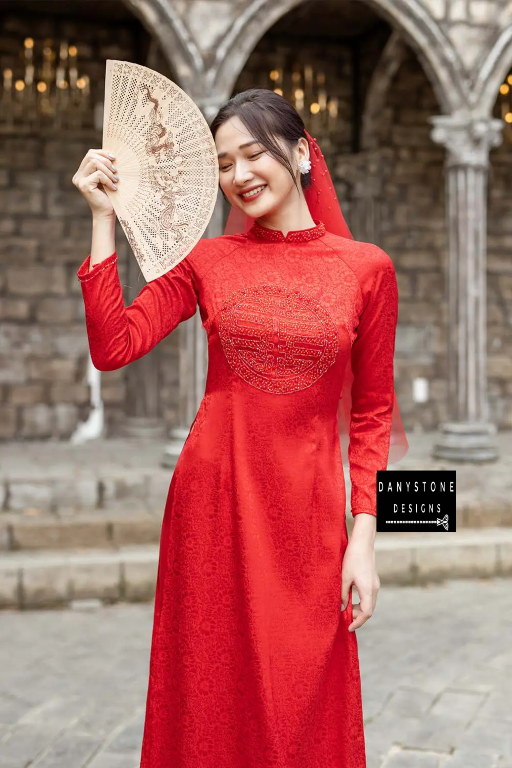 Bride smiling in a Red Brocade Bridal Ao Dai with 2 wedding panels, showcasing traditional elegance and luxurious design.