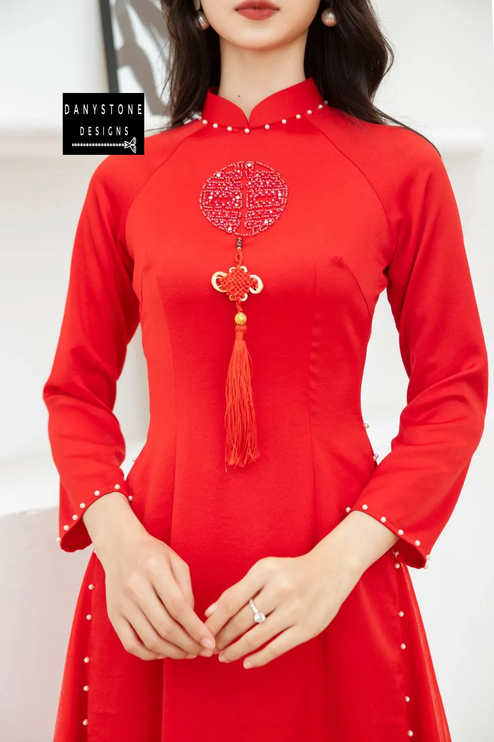 Bride wearing a Bright Red Silk Wedding Ao Dai, showcasing the elegant wedding detail on the chest and pearl accents.