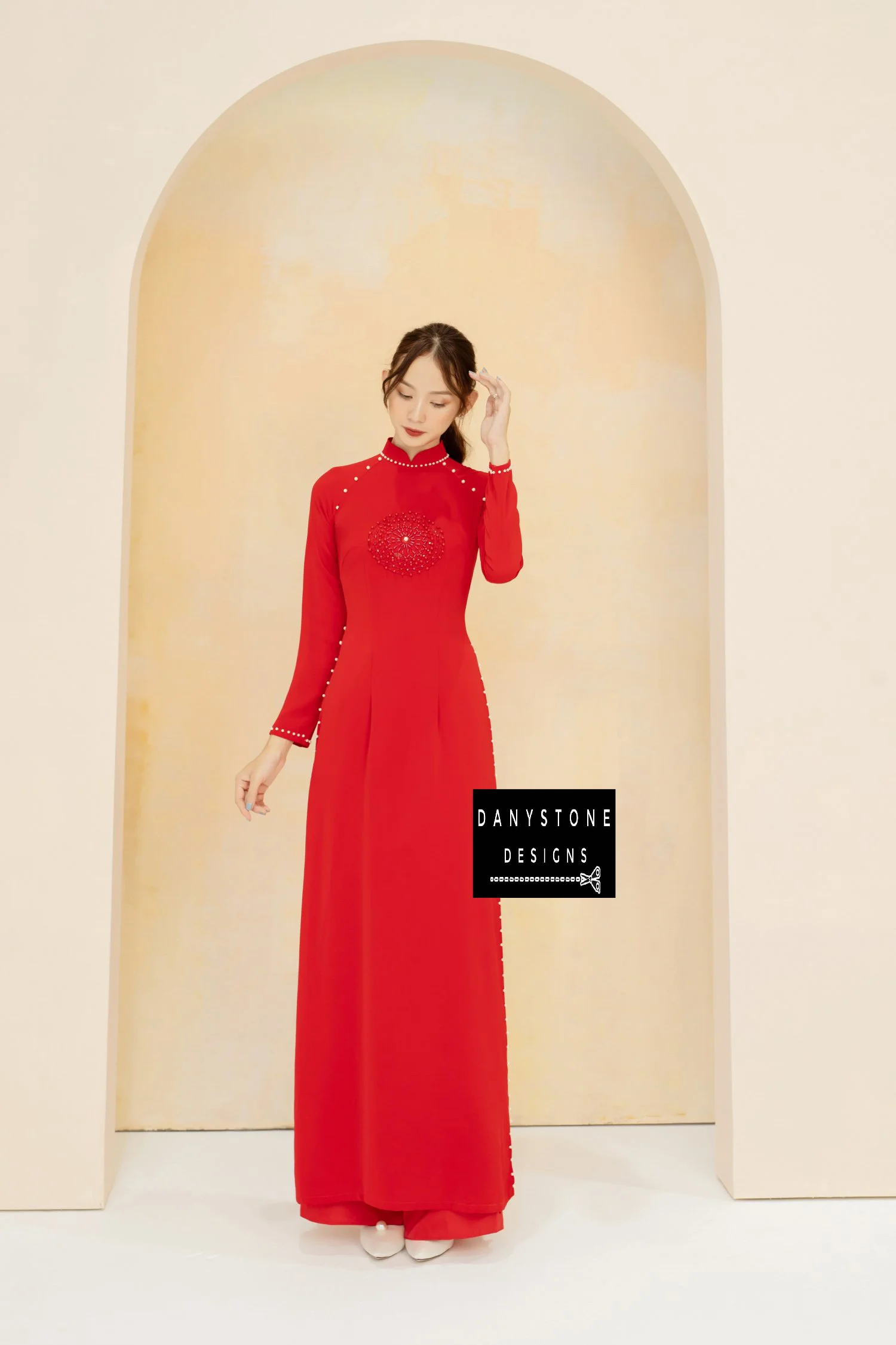 Luxurious red silk Áo Dài with elegant pearl and leather details, worn by a bride.