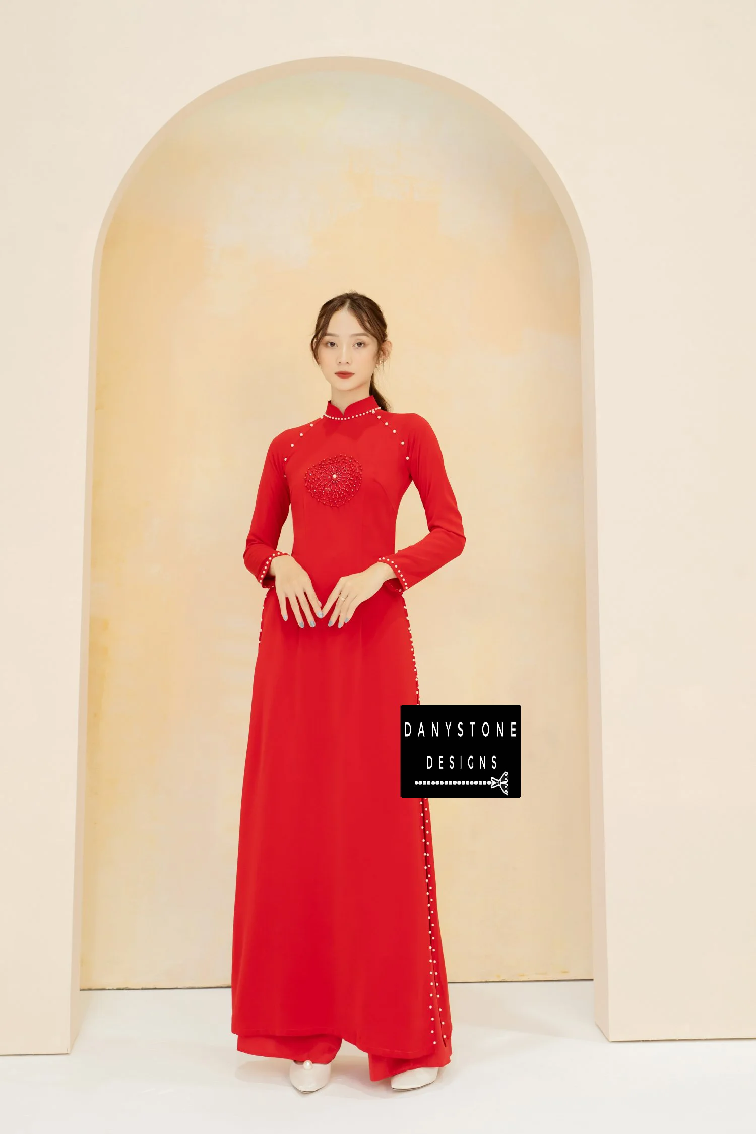 Luxurious red silk Áo Dài with elegant pearl and leather details, worn by a bride.