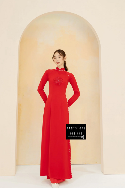 Elegant woman wearing a red silk bridal Áo Dài with round leather and pearl details.