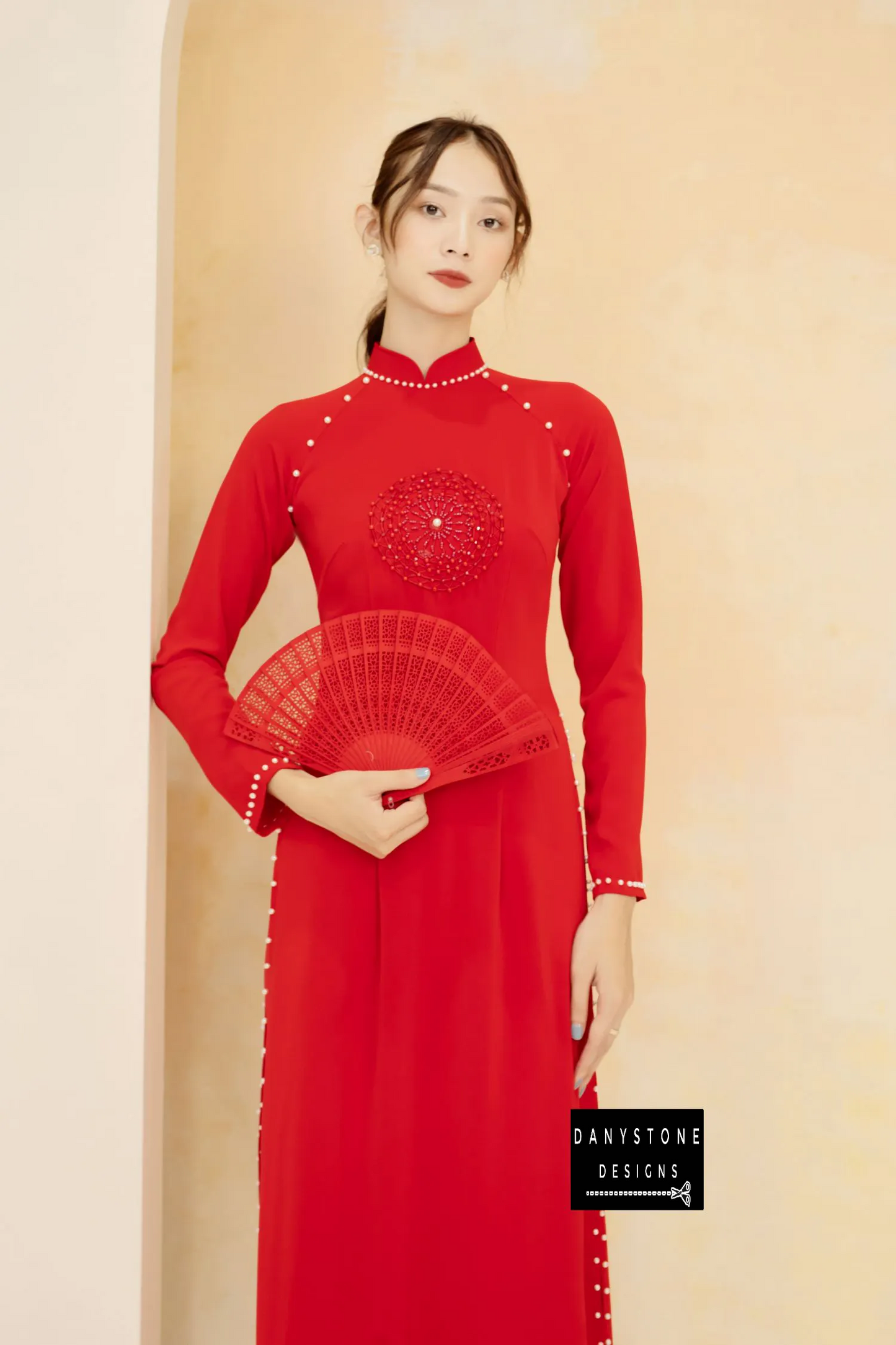 Woman in a red silk Áo Dài, featuring a radiating circular pattern with pearls.