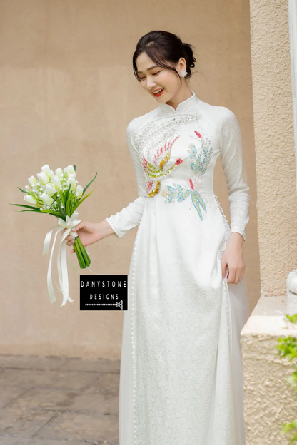 Bride wearing an Elegant White Brocade Bridal Ao Dai with phoenix collar and pearl edges, showcasing traditional aristocratic beauty.