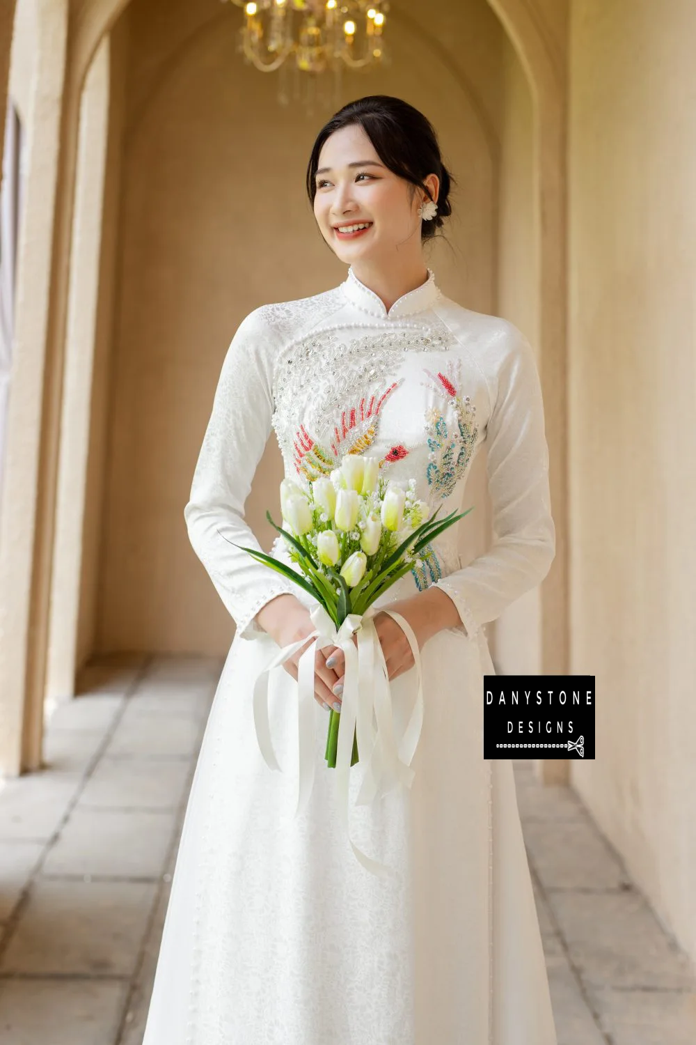 Bride holding a bouquet in the White Brocade Bridal Ao Dai, illustrating the pure and luxurious beauty of the dress.