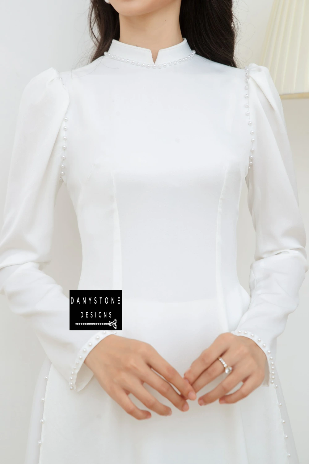 Close-up view of the Graceful White Silk Bridal Ao Dai, highlighting the puffed sleeves and pearl trim along the neckline and shoulders.