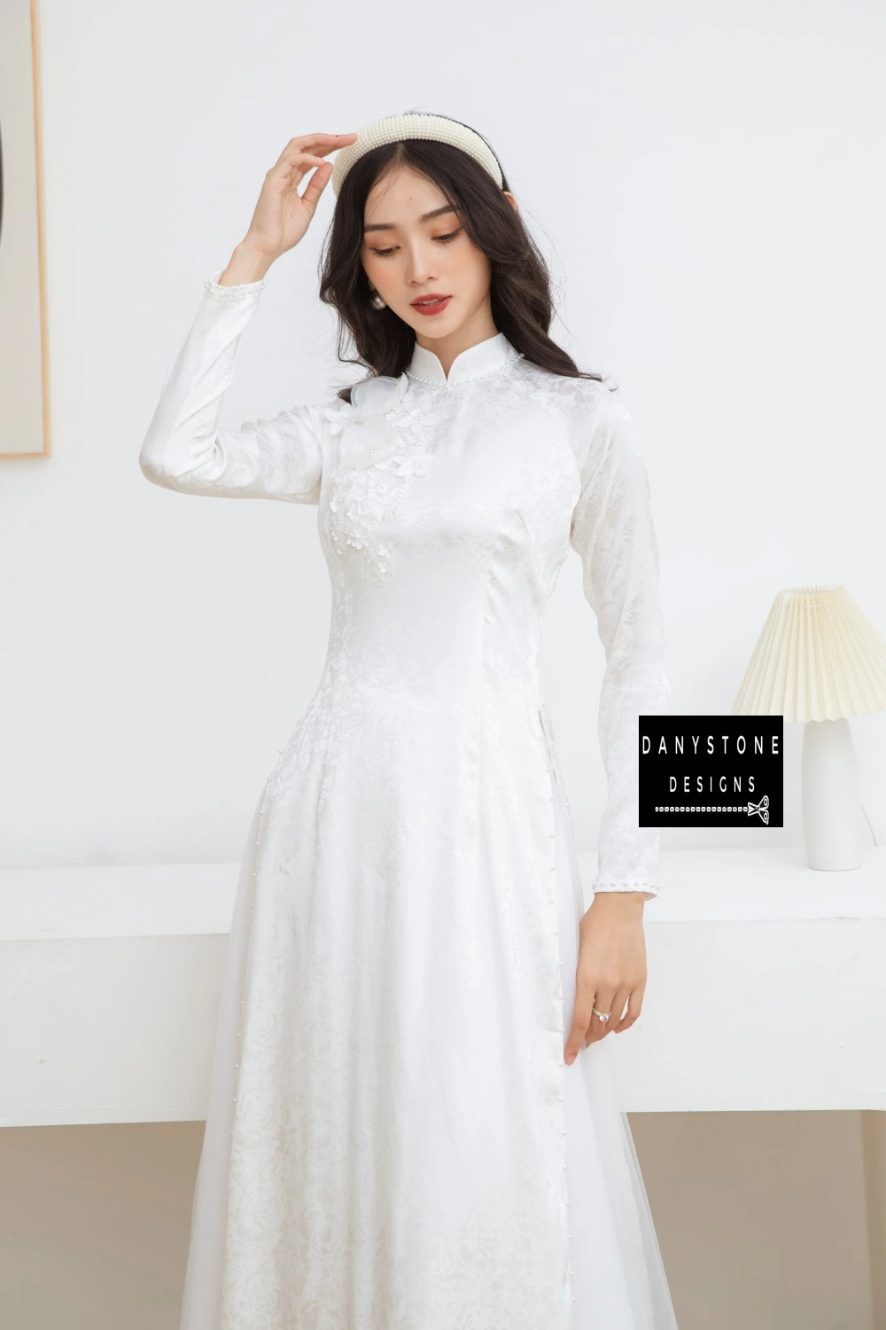 Side profile of a bride in the White Brocade Bridal Ao Dai, emphasizing the pearl-embellished collar and floral details.